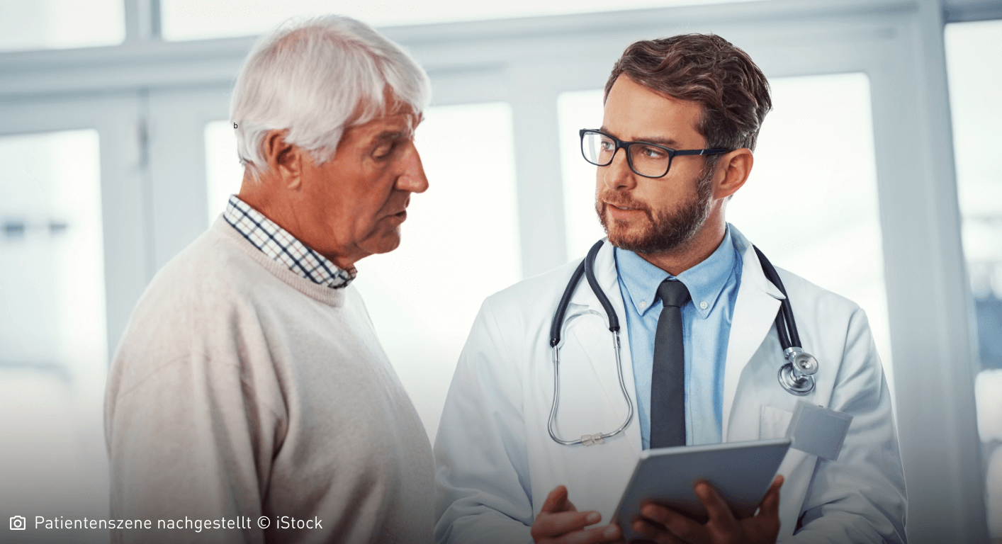 Arzt erklärt älterem Mann etwas und deutet auf ein Tablet in seiner Hand: Für eine Mastozytose gibt es verschiedene Therapieansätze.